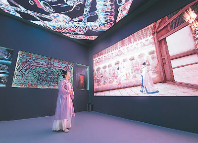 第十九屆中國（深圳）國際文化產(chǎn)業(yè)博覽交易會設(shè)立了“數(shù)字中國——AI時代的文化創(chuàng)新”主題展區(qū)。一批大數(shù)據(jù)、人工智能等技術(shù)應(yīng)用文化企業(yè)參展。數(shù)字化助力中華傳統(tǒng)文化“活”起來，也為現(xiàn)場觀眾帶來了新鮮的觀展體驗。   圖為一名身著傳統(tǒng)服飾的觀眾在文博會甘肅展臺觀看數(shù)字敦煌展覽。   新華社記者 梁 旭攝