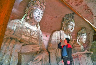 義務(wù)文保員在對重慶市大足區(qū)寶頂鎮(zhèn)香山社區(qū)的佛祖巖摩崖造像進(jìn)行巡查。新華社記者 王全超攝